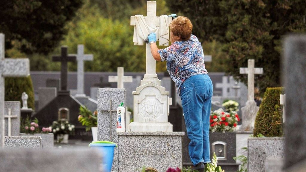 Una mujer limpia la tumba de un ser querido