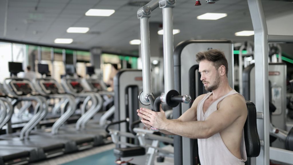 Deportista ejecutando el ejercicio 'Reverse Pec-Deck'.