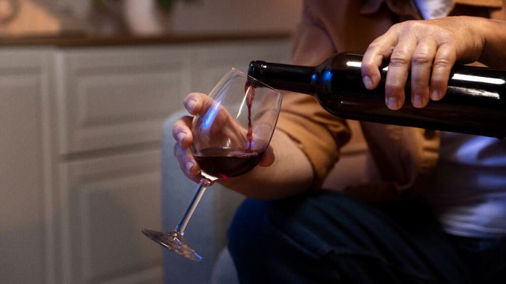  Persona sirviéndose una copa de vino tinto
