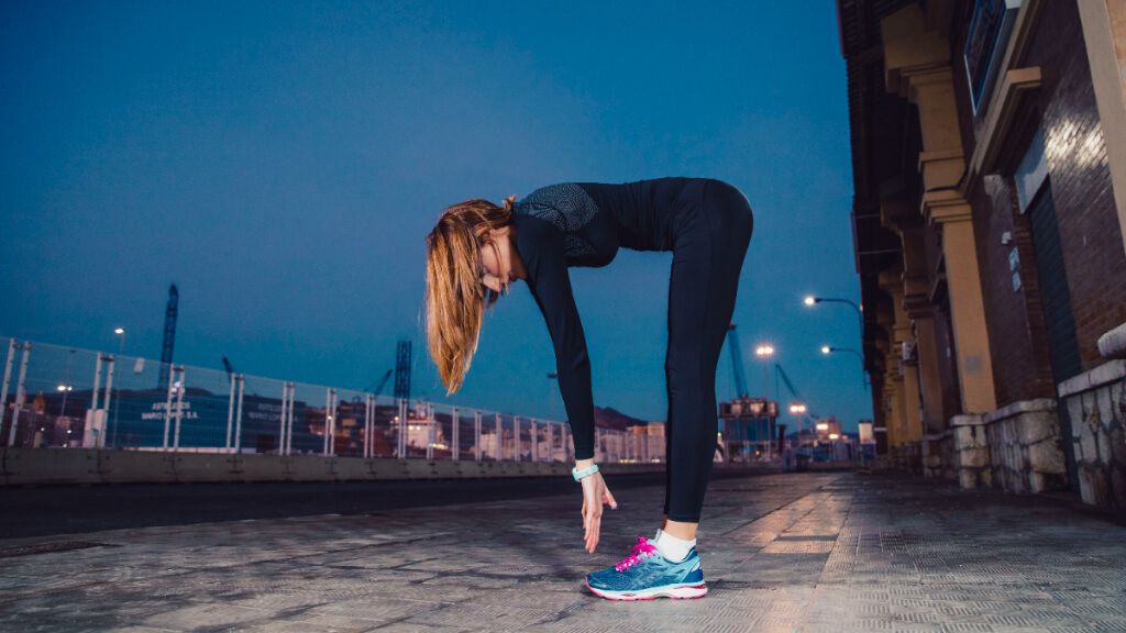 Mujer entrenando en la calle mientras se hace de noche (Freepik)