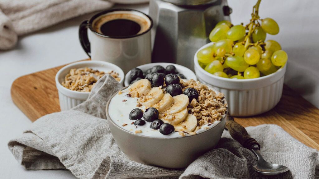  Cuenco de uvas, bol de yogur con frutas, café, muesli