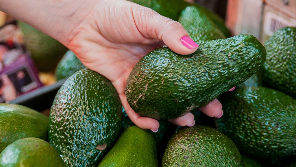  Mujer cogiendo un aguacate de un comercio