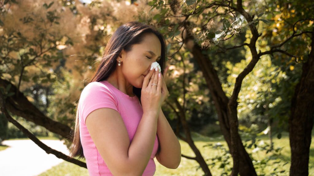  Mujer sonándose la nariz en un parque (Freepik)