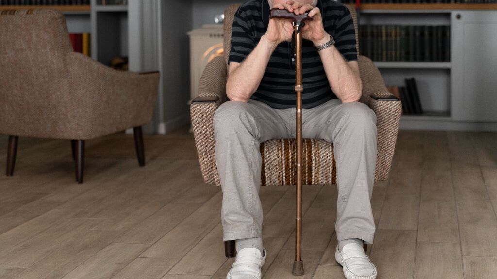  Hombre mayor sentado en un sofá con un bastón