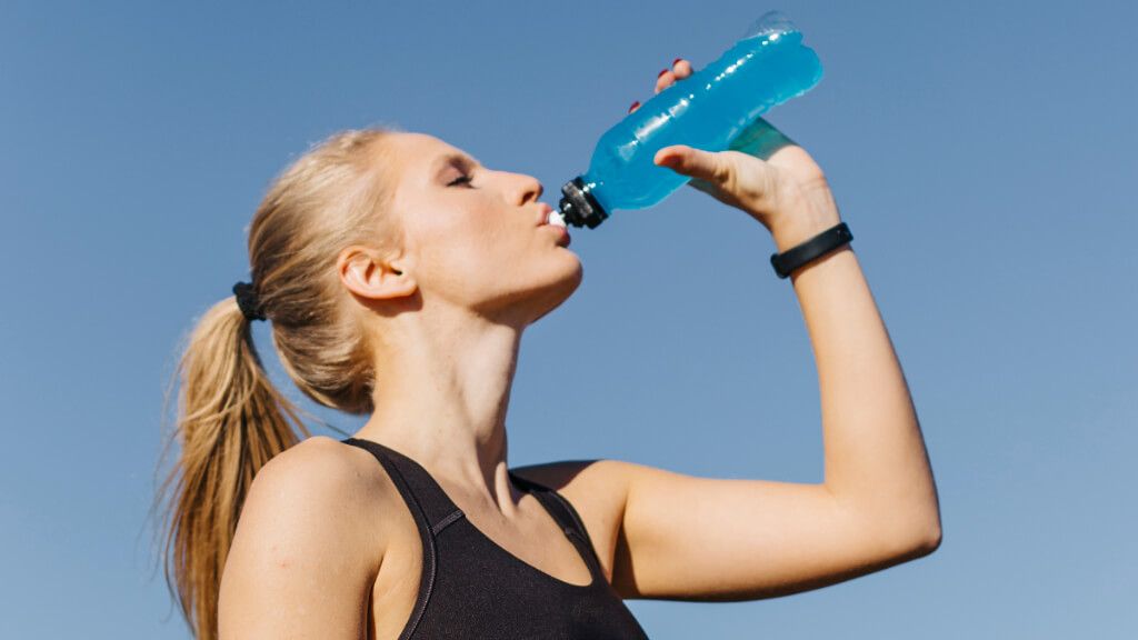  Mujer con ropa deportiva tomando una bebida isotónica