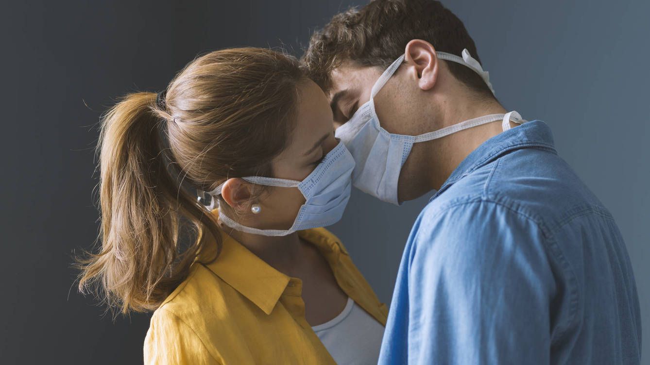  Dos personas con mascarillas dándose un beso