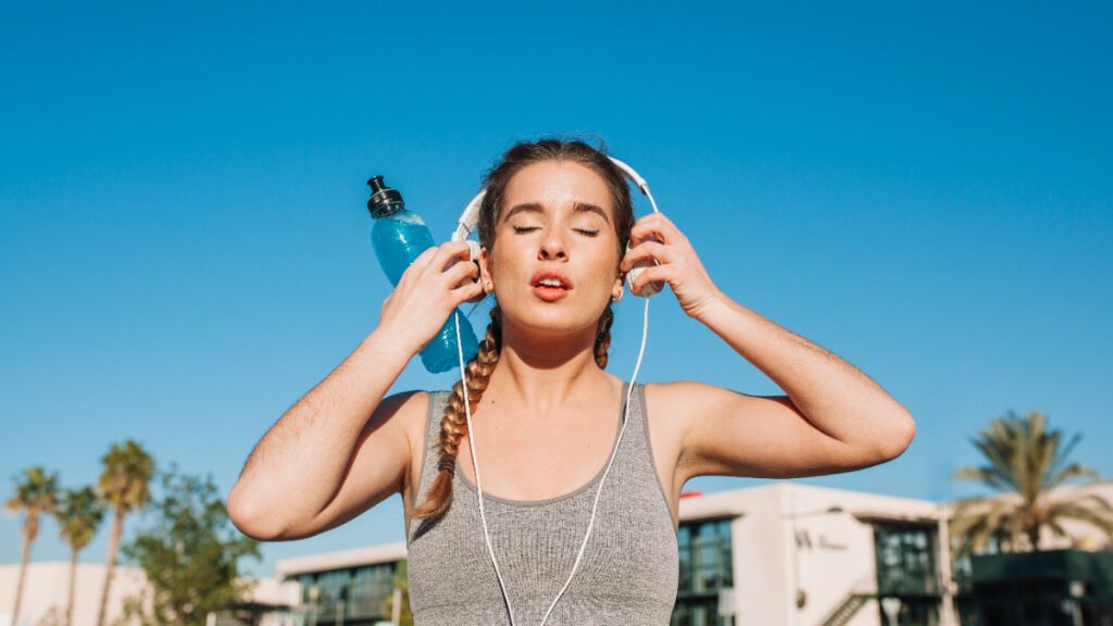 Mujer haciendo deporte al aire libre mientras se coloca los cascos
