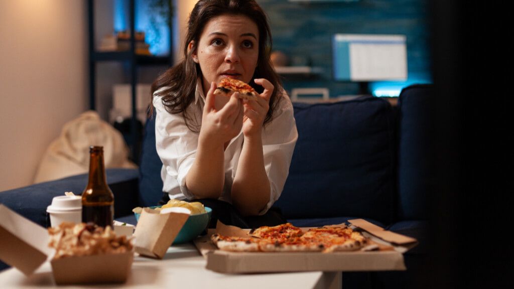 Mujer estresada comiendo alimentos poco saludables