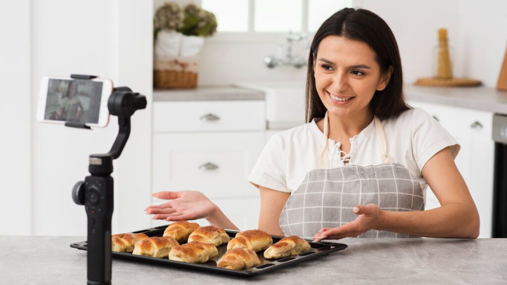 Mujer grabándose con un móvil mientras prepara unos bollitos