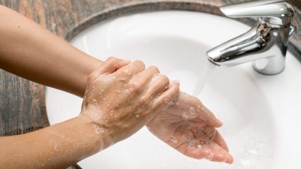  Persona lavándose las manos con agua y con jabón