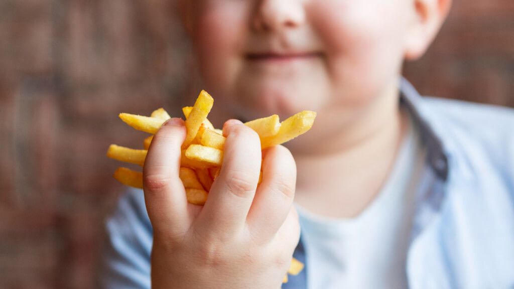  Niño comiendo patatas fritas con las manos (Freepik)