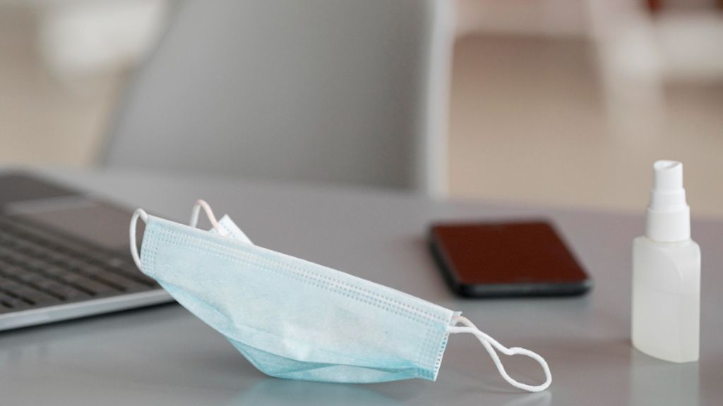 Mascarilla y desinfectante de manos en una mesa de trabajo