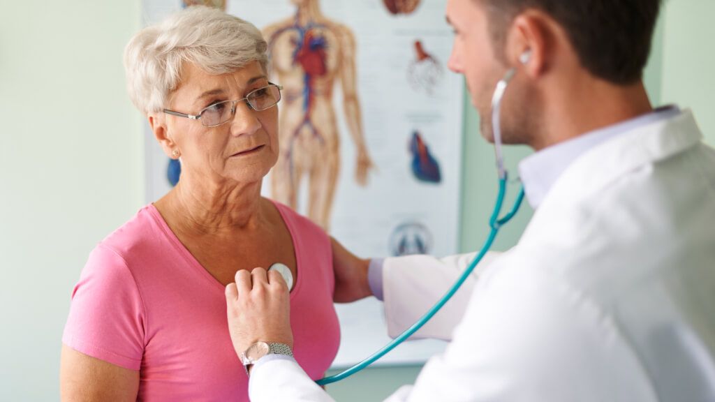  Médico auscultando con un fonendoscopio a una mujer de edad avanzada
