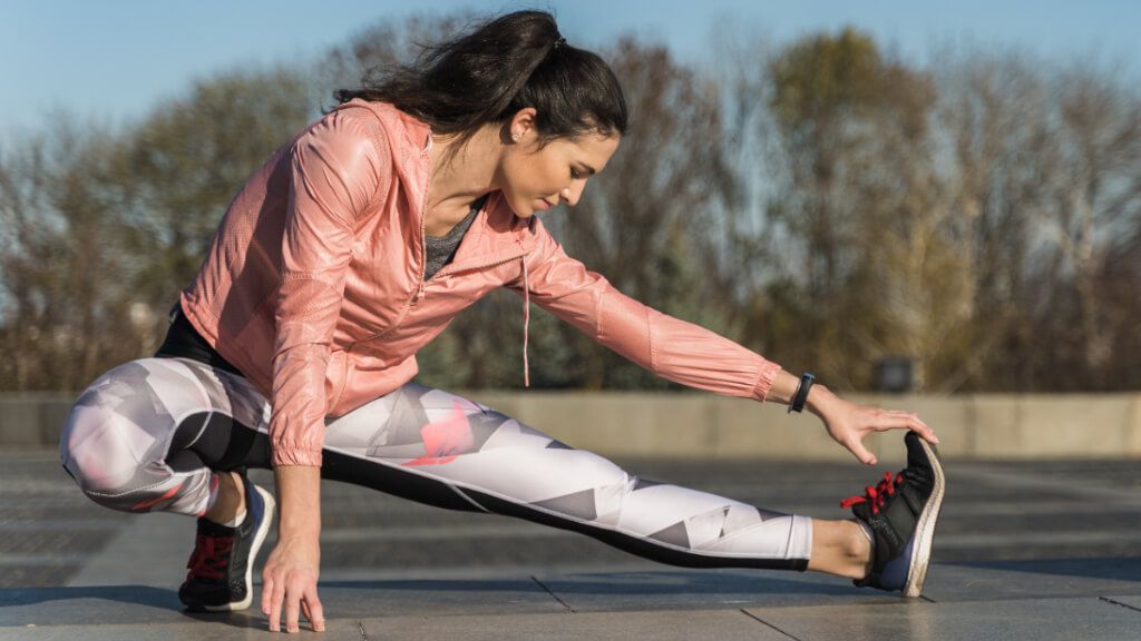  Mujer estirando en la calle antes de hacer ejercicio físico (Freepik)