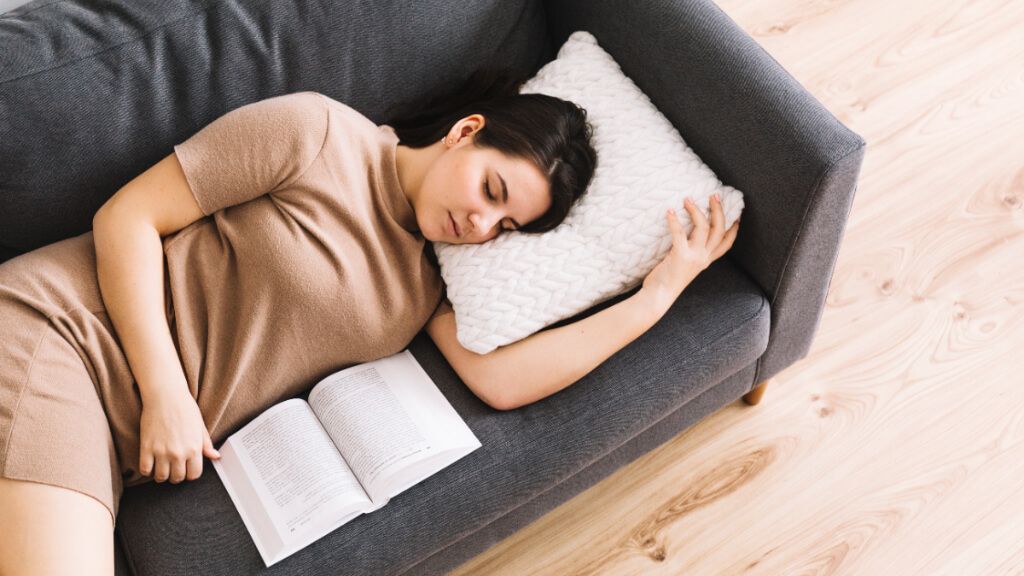  Mujer acostada en un sofá mientras lee un libro (Fuente: Freepik)