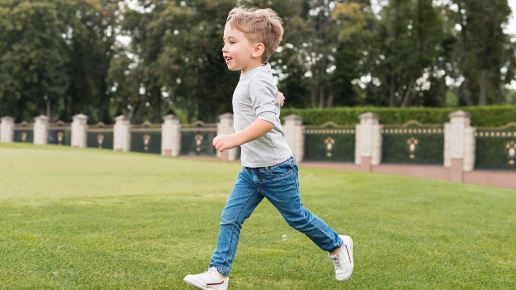 Niño corriendo por el césped de un parque