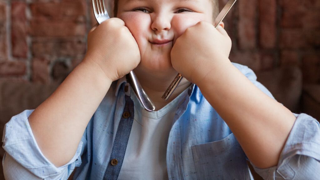  Niño con sobrepeso esperando a que le traigan la comida (Fuente: Freepik)