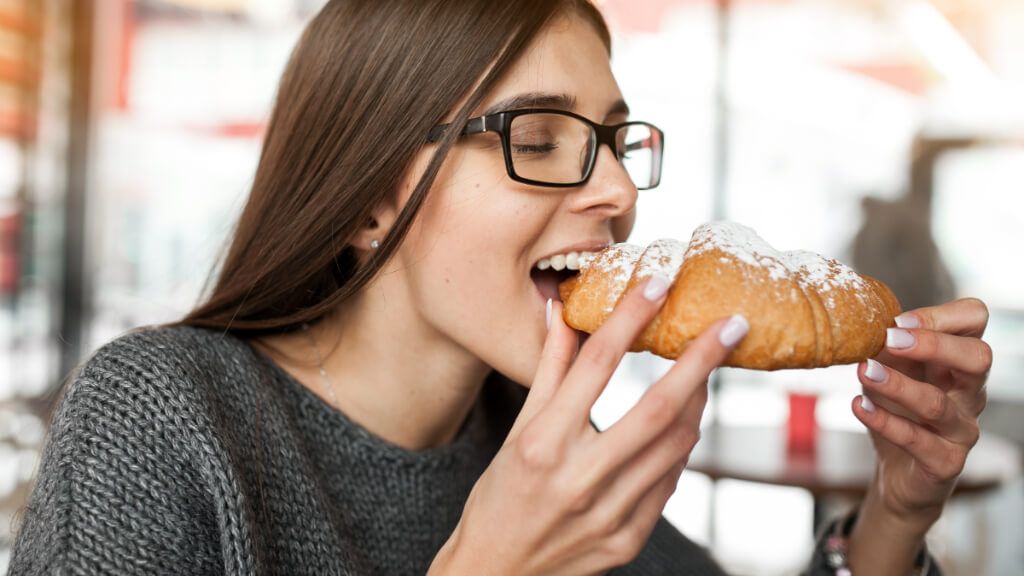  Mujer comiendo un cruasán con azúcar