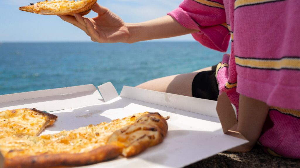 Gente comiendo pizza en la playa