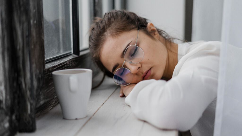  Chica dormida en el alféizar de una ventana con un café al lado