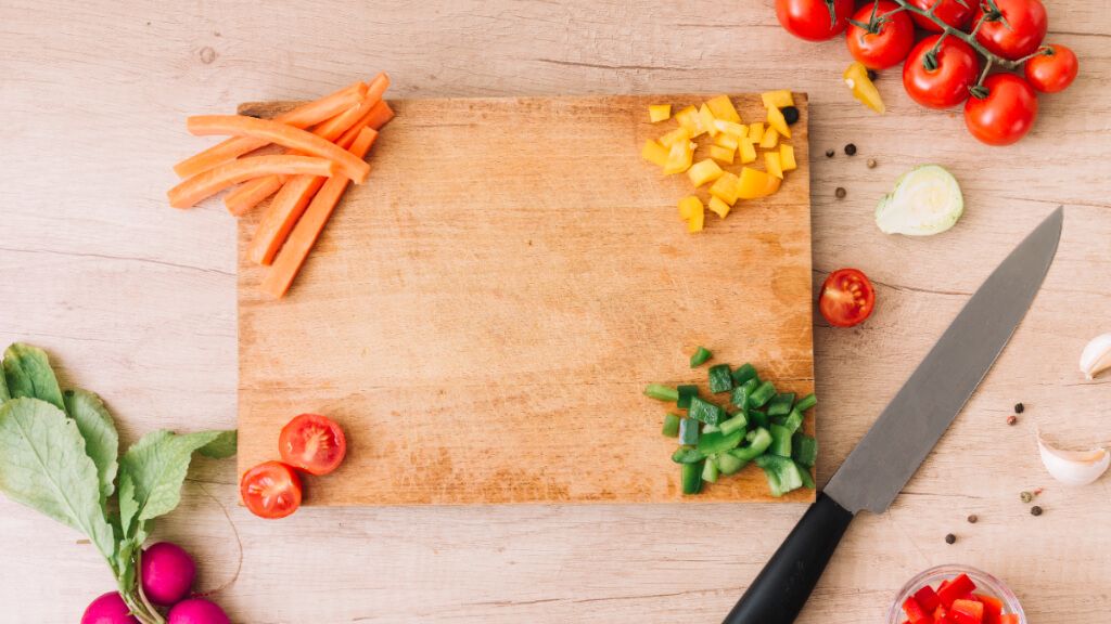 Tabla de cortar de madera con varios alimentos cortados sobre ella