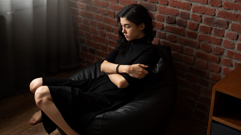 Mujer sentada en una silla con síntomas de ansiedad