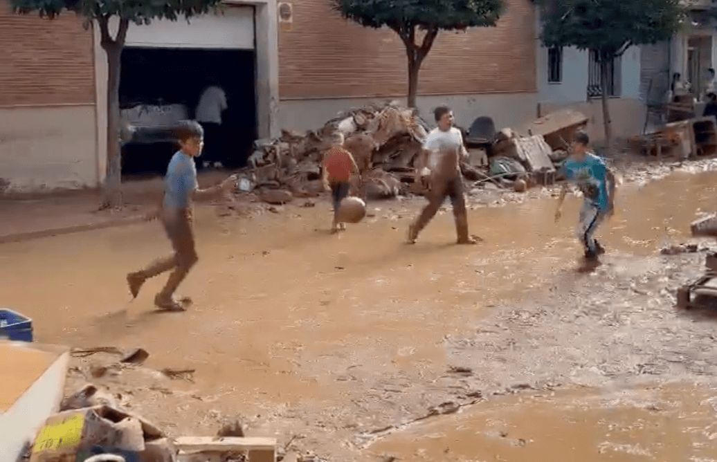  Niños juegan a fútbol en medio del barro de Aldaia.