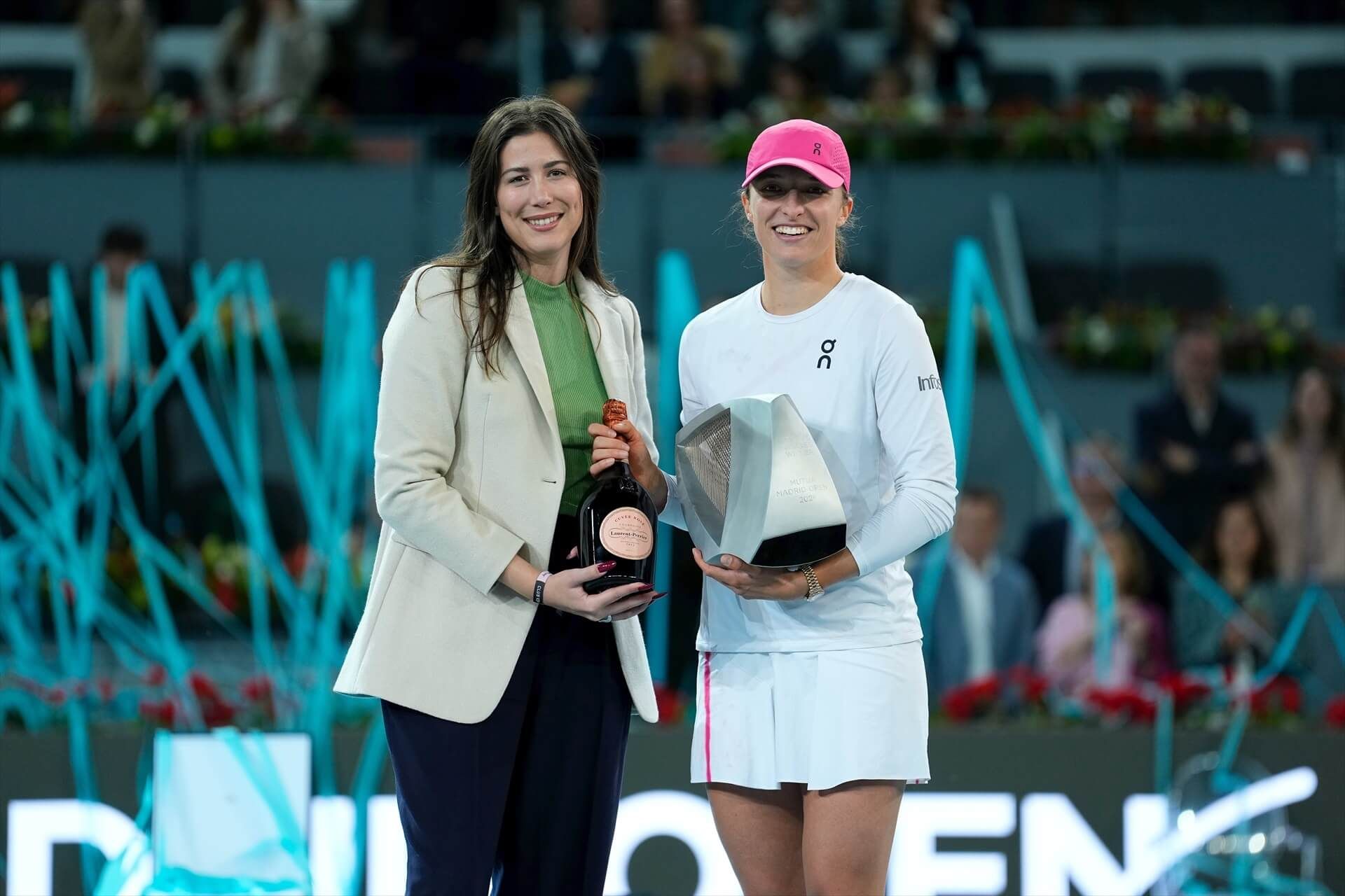  Garbiñe Muguruza e Iga Swiatek posan con el trofeo y la botella