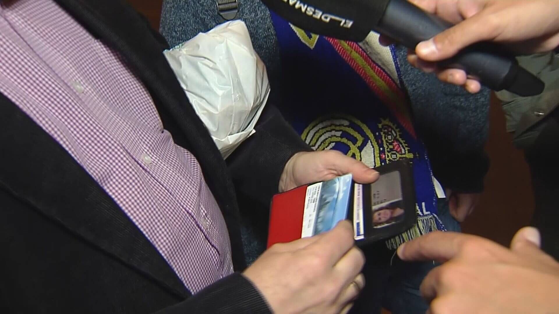 Un aficionado del Atlético enseña su abono del Real Madrid