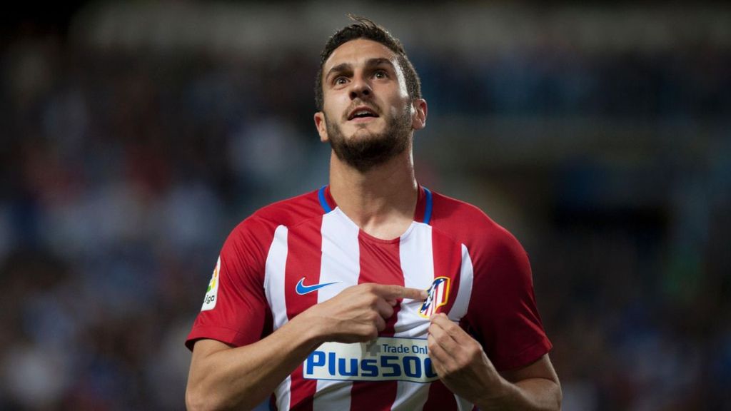 Koke señala el escudo durante un partido