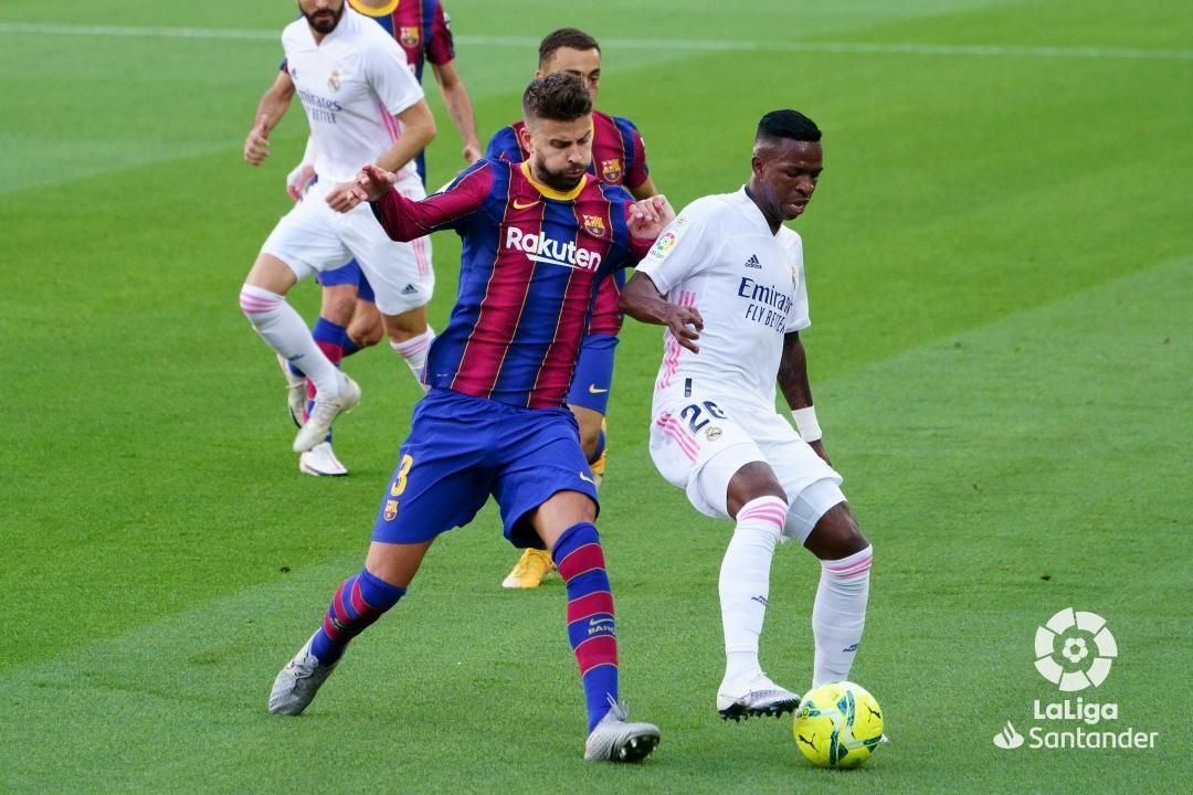 Piqué y Vinícius pelean por una pelota.