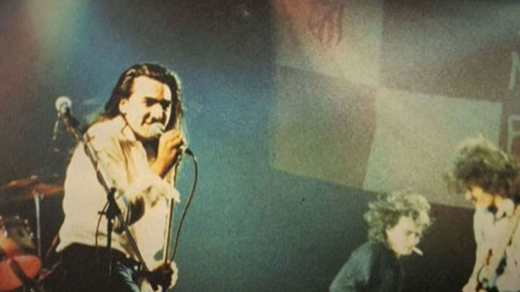 Iñaki Glutamato en concierto en la década de los ochenta con la bandera del Atlético de Madrid al fondo.