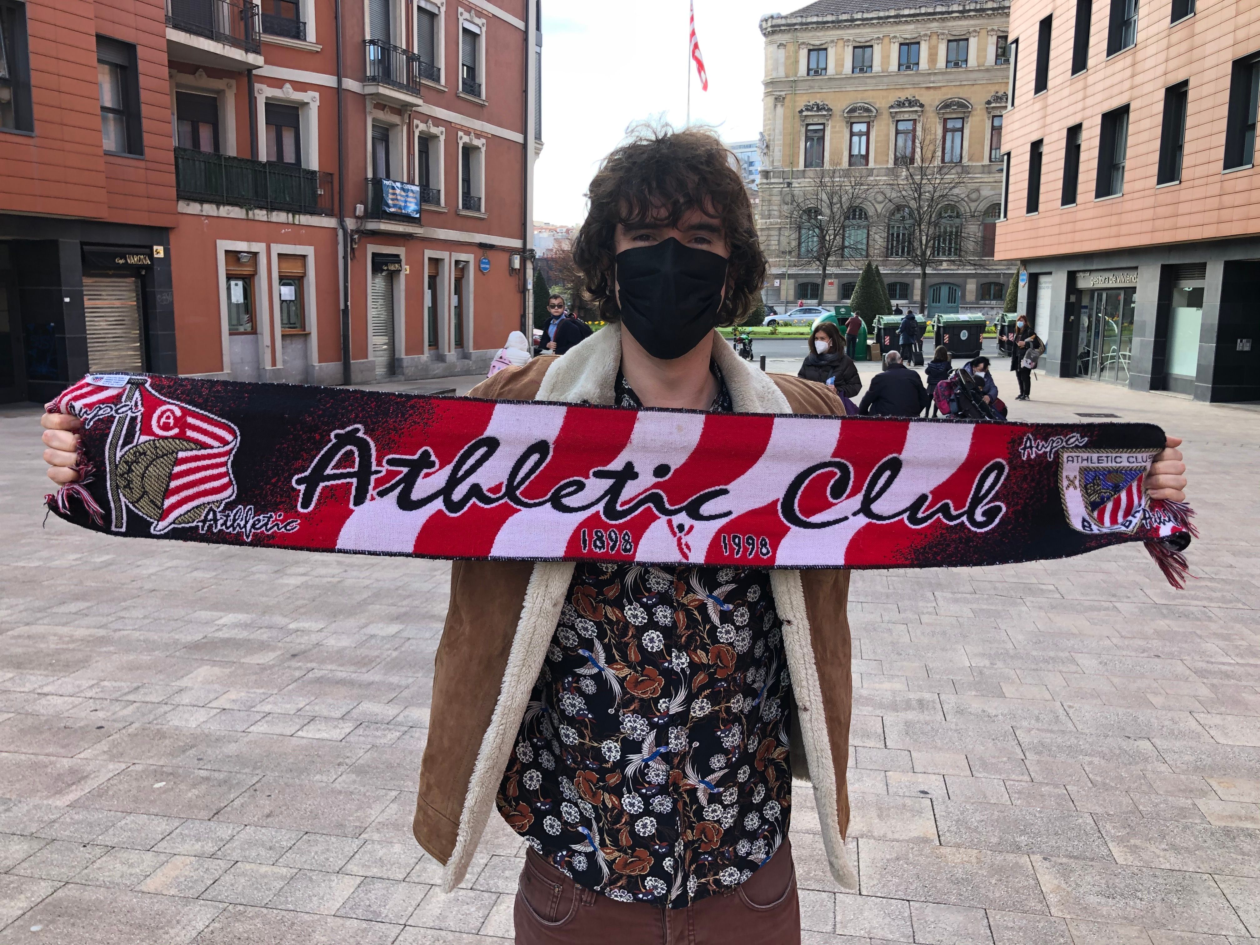 El actor bilbaíno Lander Otaola despliega junto al Ayuntamiento la bufanda del Athletic Club.