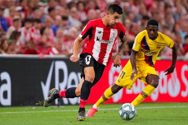 Yuri Berchiche perseguido por Dembélé.