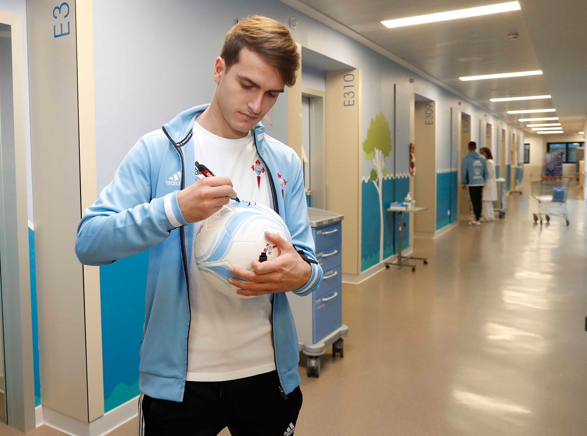  Denis Suárez estampa su firma en un balón durante la visita al hospital Álvaro Cunqueiro.
