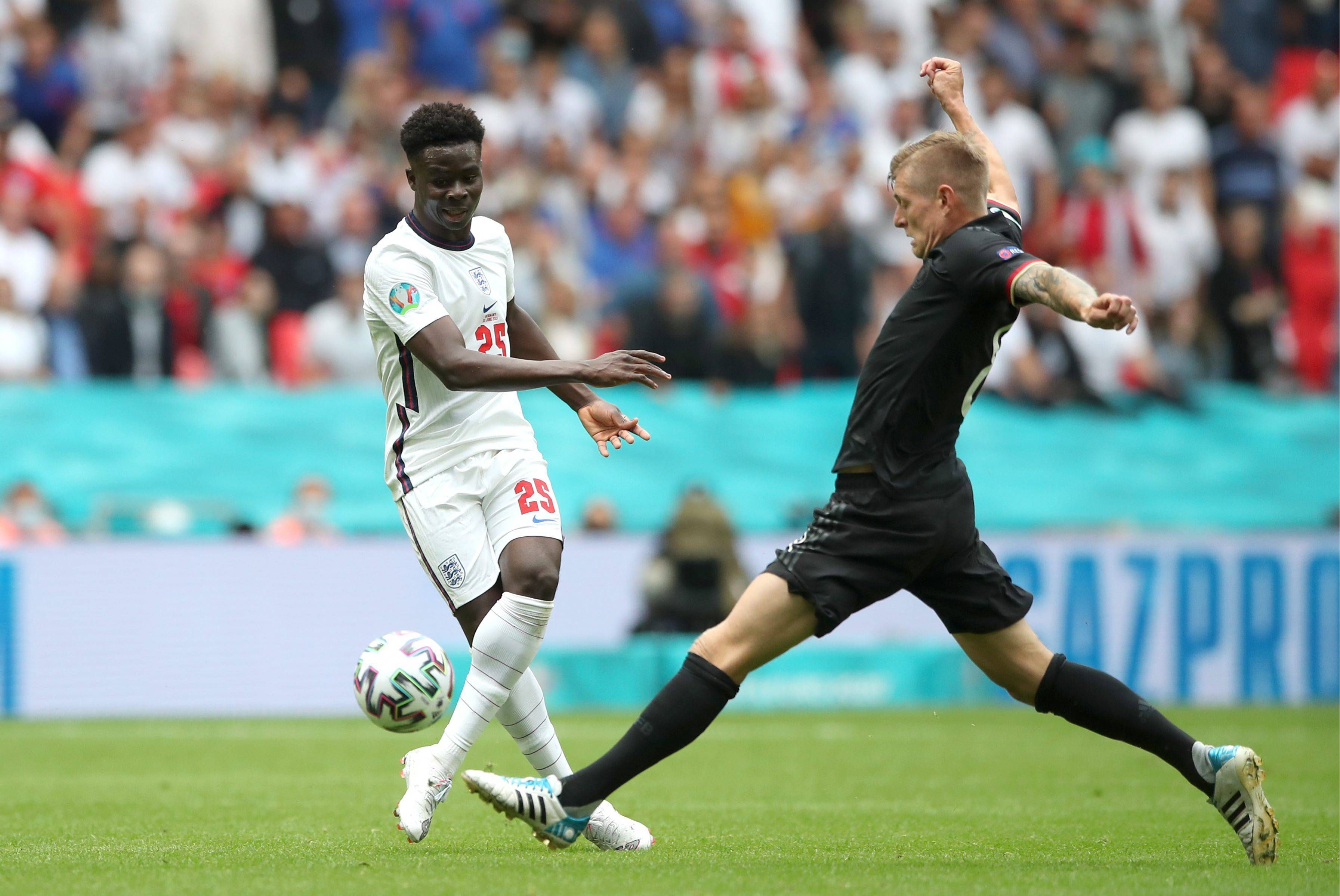  Toni Kroos intenta robar un balón a Bukayo Saka.