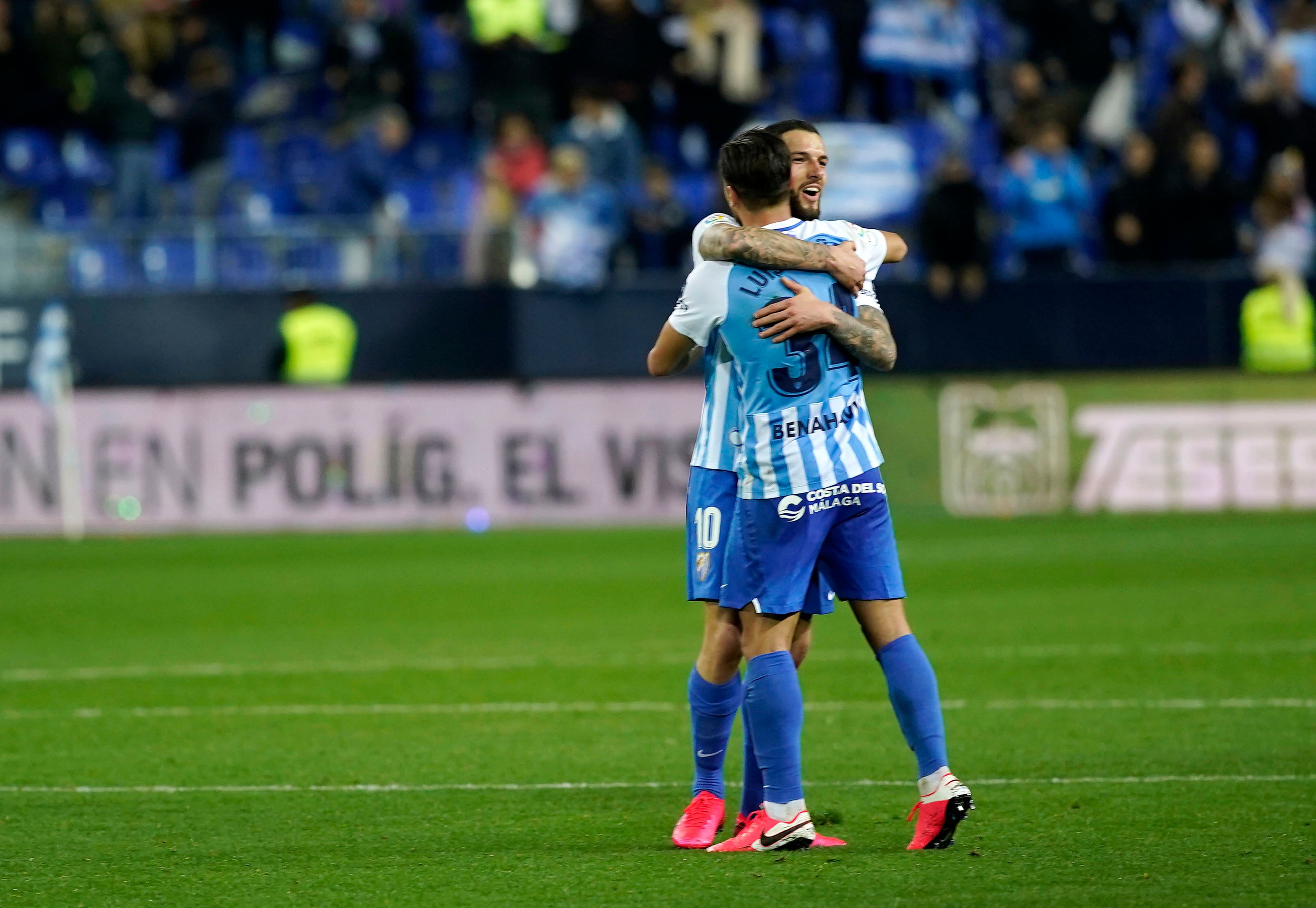Tete y Luis Muñoz se abrazan sobre el verde.