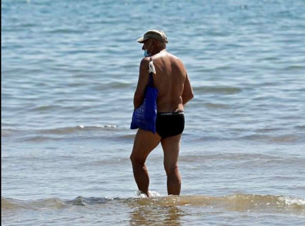  Bañista con mascarilla en la playa de València