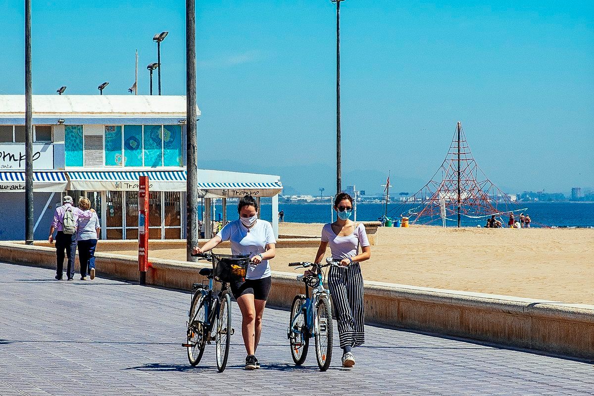 Ciclistas con mascarillas en la playa de Valencia