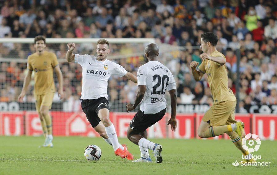 Toni Lato conduce ante Foulquier durante el Valencia-Barcelona.