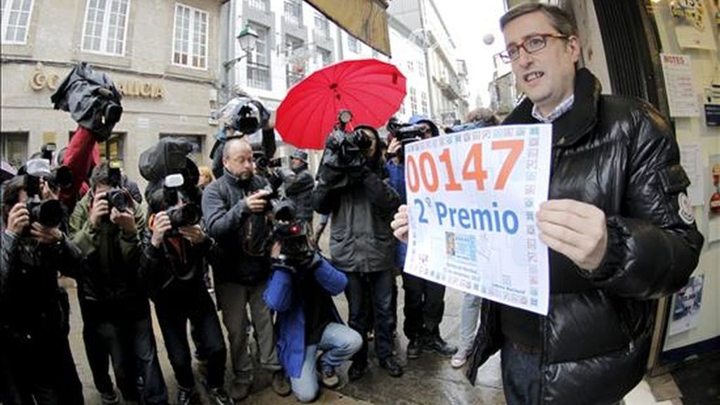 El administrador del despacho de lotería número tres de la Rúa del Vilar (Santiago de Compostela), José Luis Tojo Núñez, muestra el cartel con el número 00147, agraciado con el segundo premio de la Lotería de Navidad. EFE