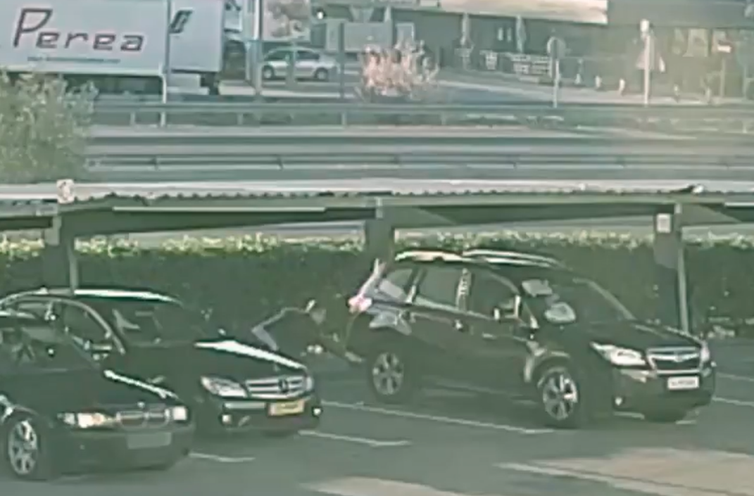 Un ladrón pinchando la rueda de un coche para robarle después al conductor