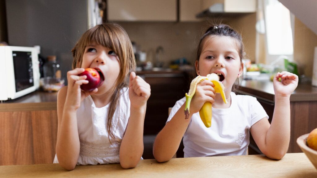 Dos niñas comiendo fruta