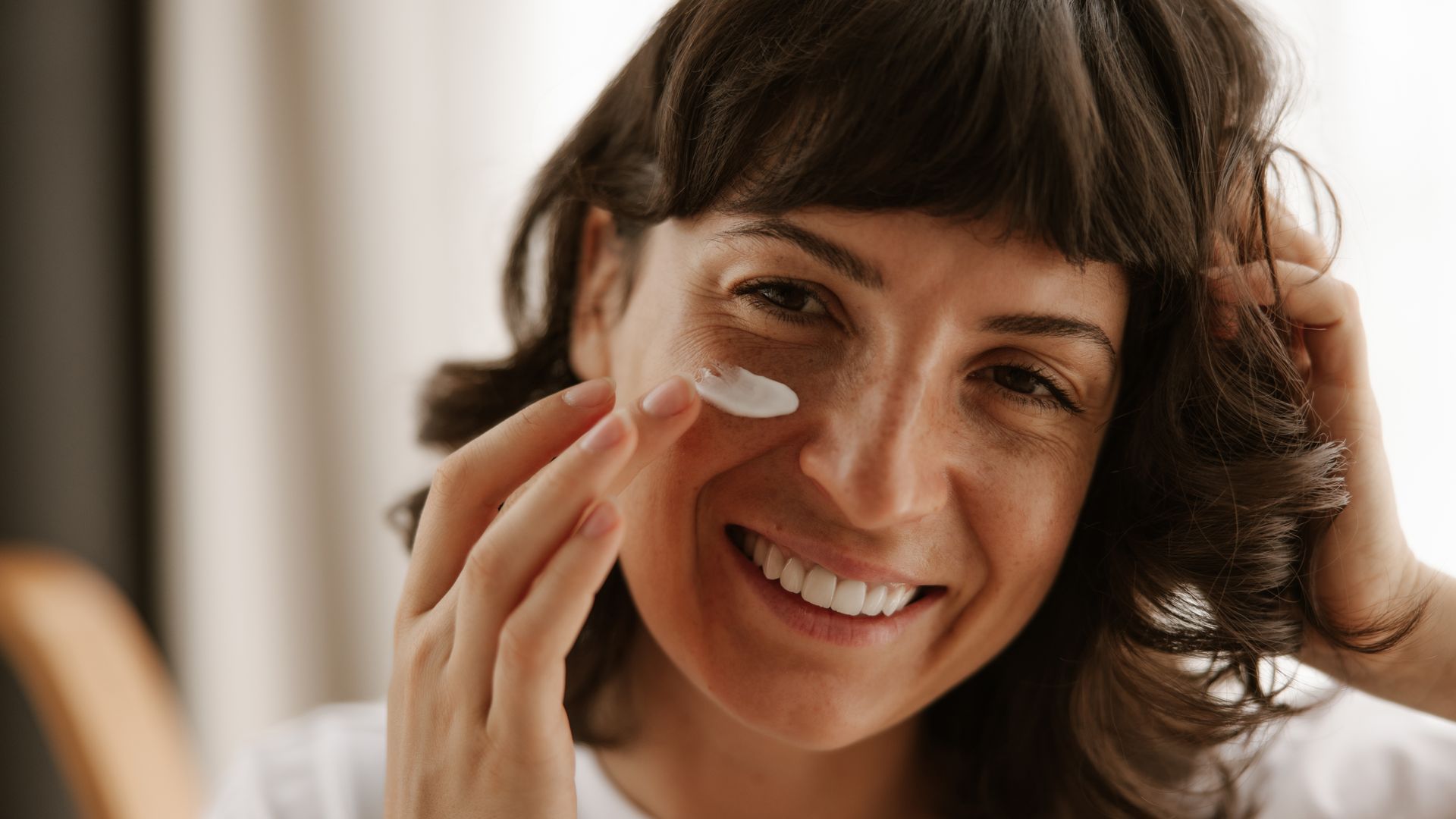 Una mujer echándose crema en la cara