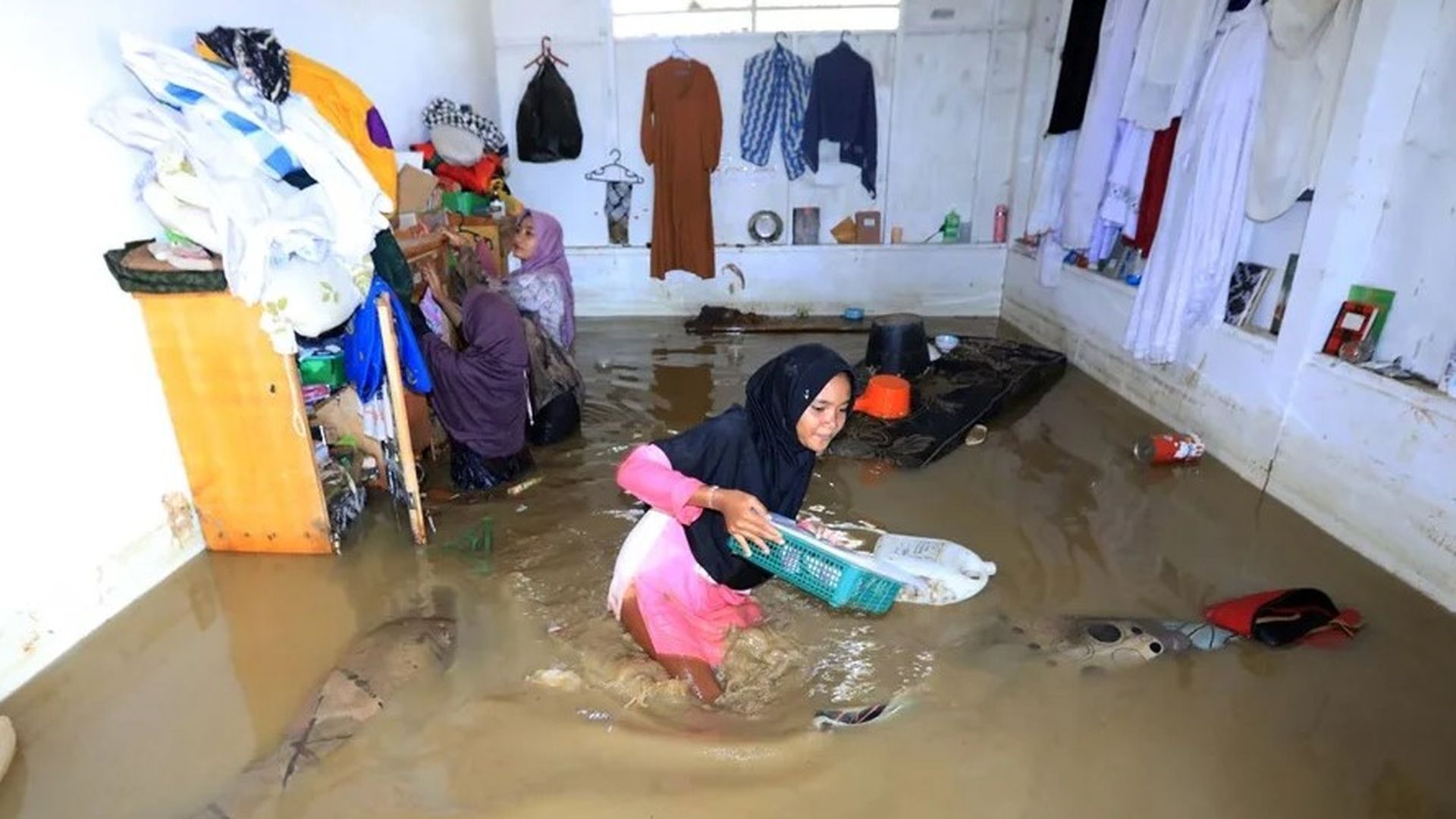Una mujer trata de recuperar sus pertenencias durante la inundación de su vivienda en Jaya Aceh, Indonesia.