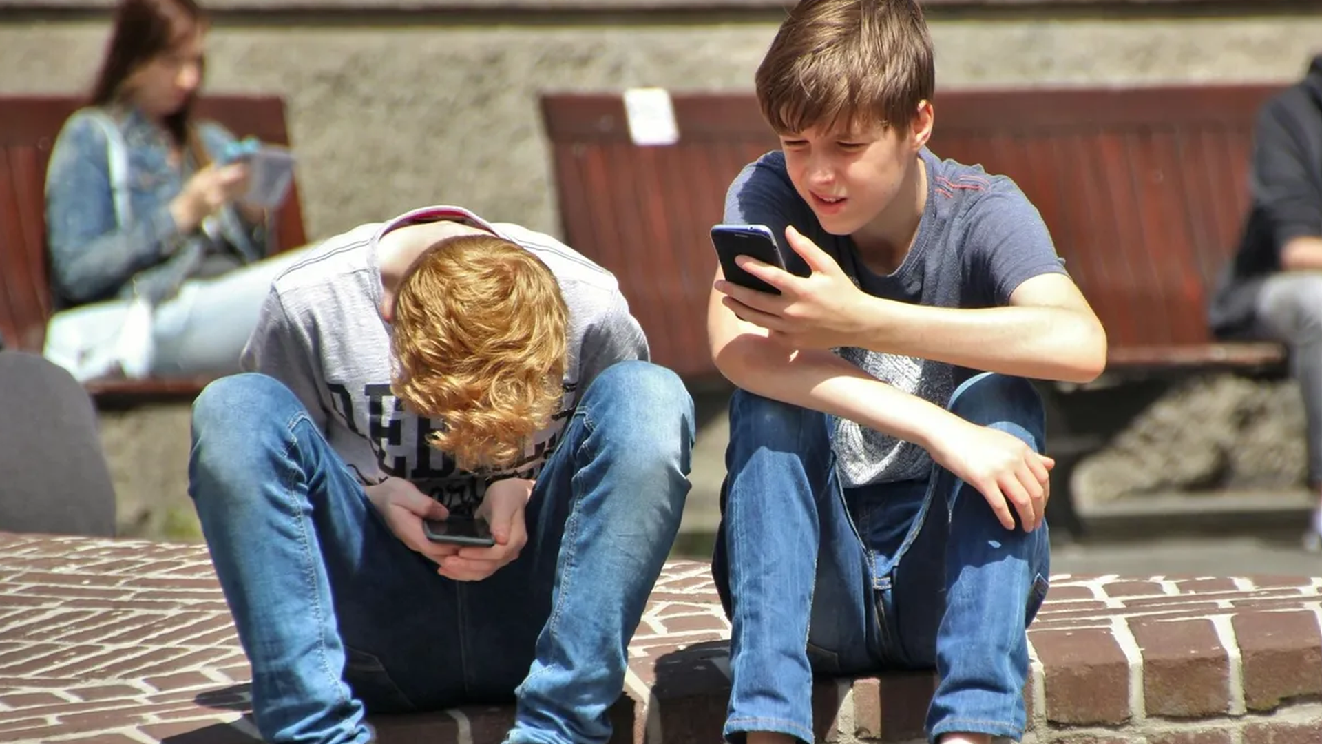 Dos menores utilizando el móvil