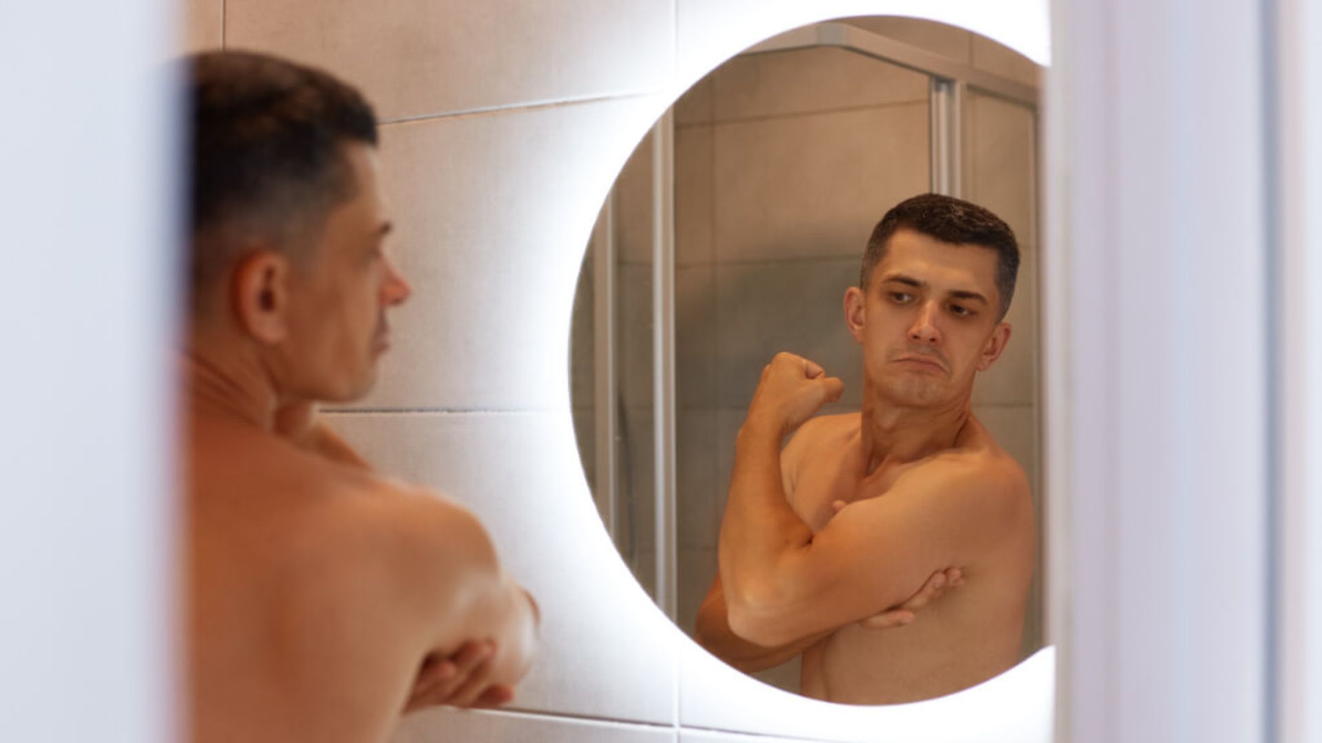 Hombre sin camiseta mirándose en el espejo
