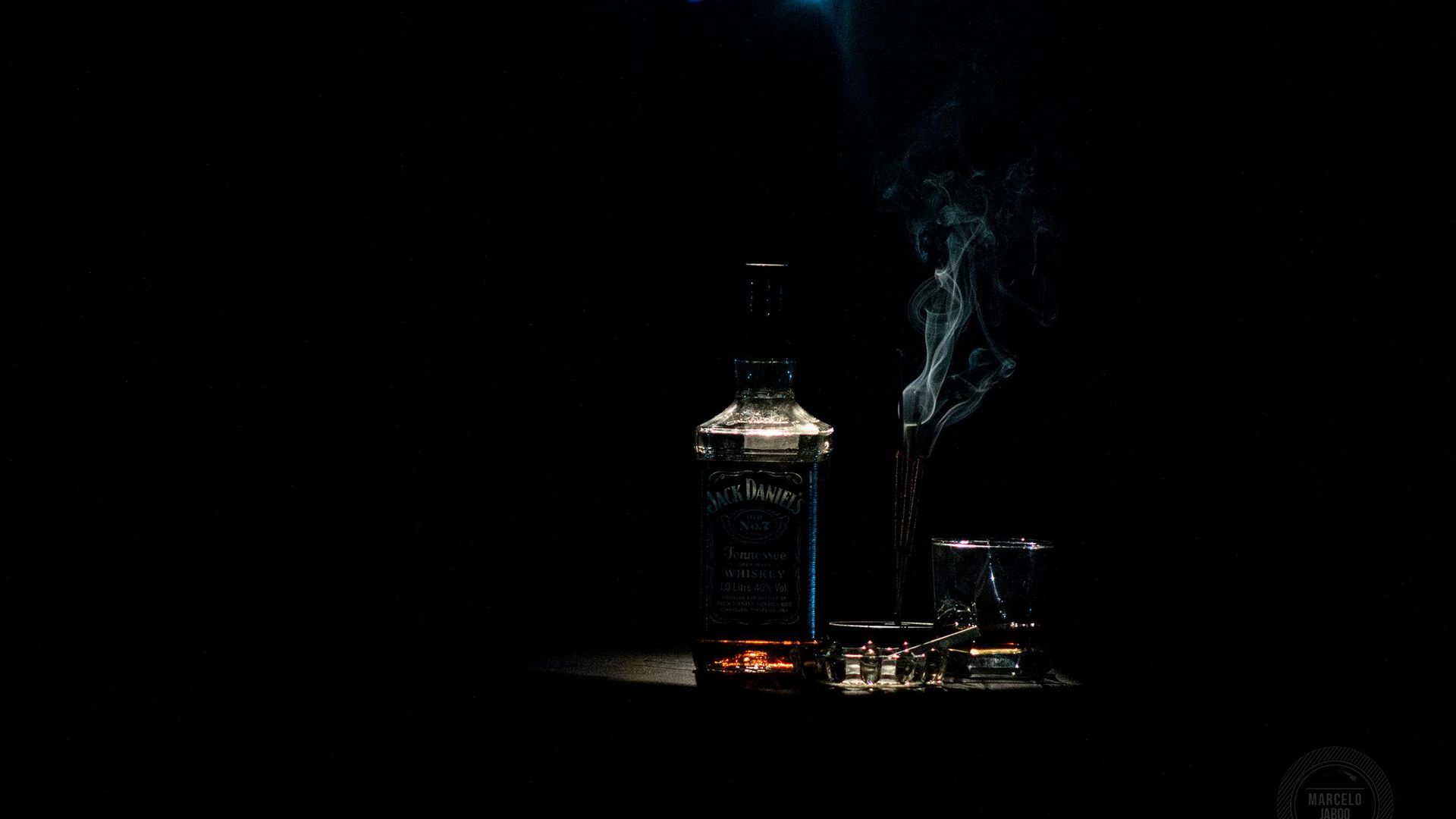 Botella de whisky, vaso y cenicero