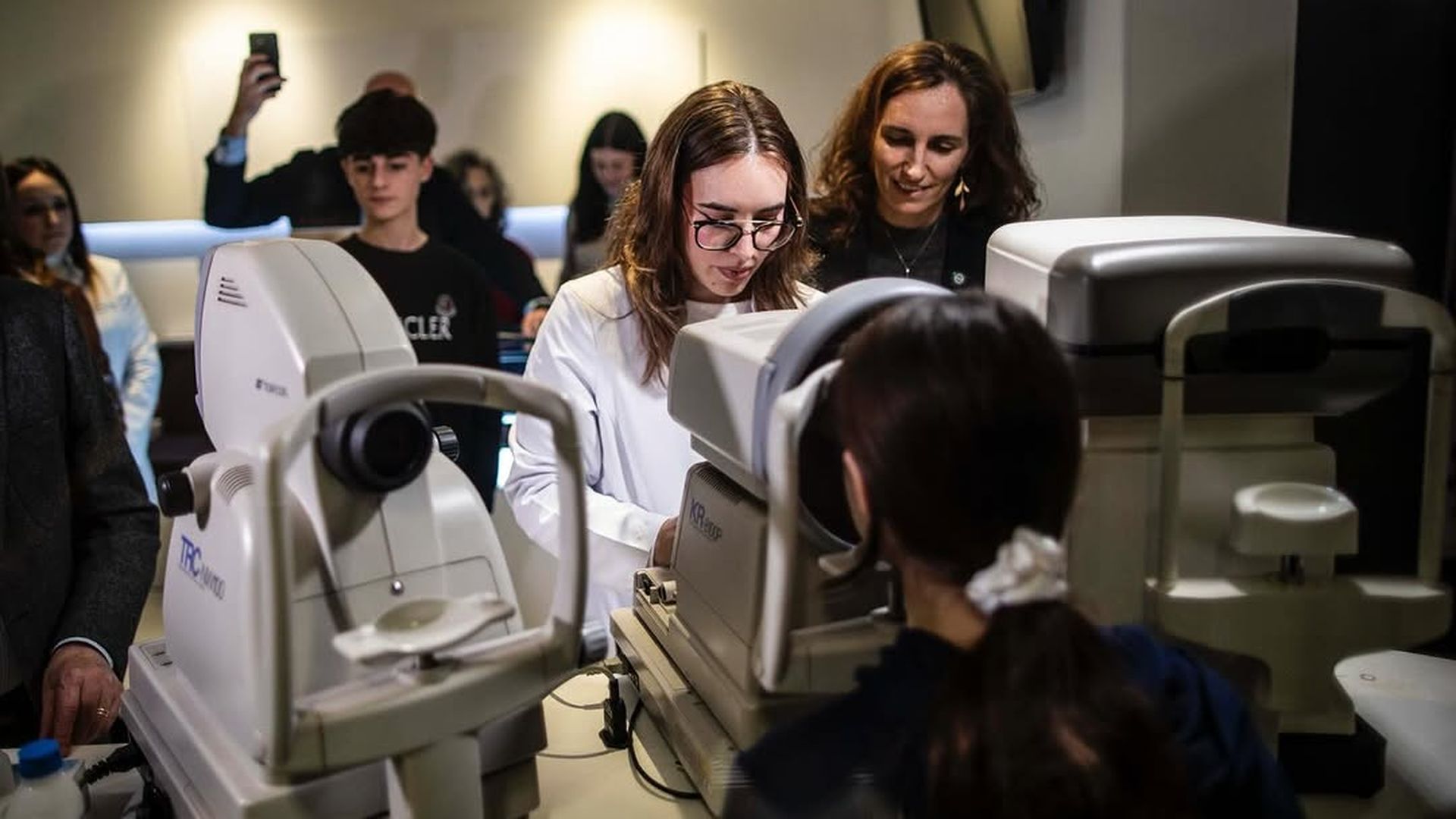 Óptica haciendo una prueba a una niña junta a Mónica García