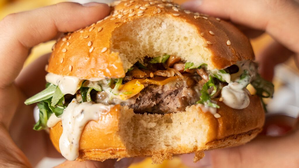  Persona comiéndose una hamburguesa de carne (Freepik)